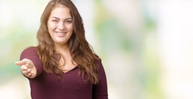 Güzel ve çekici artı boyutu genç kadın dostu sunan el sıkışma tebrik ve davet edici olarak gülümseyen izole arka plan üzerinde elbise giyiyor. Başarılı iş.