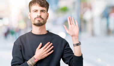 Yakışıklı delikanlı izole arka plan üzerinde göğüs ve bir sadakat sözü yemin yapma avuç, el ile küfür