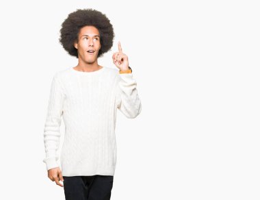 Afrikalı-Amerikalı genç afro saçlı kış kazak işaret parmağı ile başarılı fikir giyiyor. Çıktıktan ve mutlu. Bir numara.