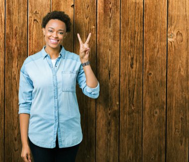 Gösterilen ve parmakları ile işaret izole arka plan üzerinde genç güzel bir Afrikalı-Amerikalı kadın ikincisi ise kendinden emin ve mutlu gülümseyerek.