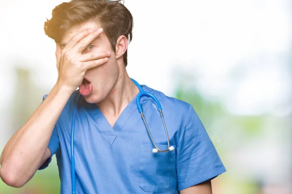Young Doctor Wearing Medical Uniform Isolated Background Peeking Shock Covering — Stock Photo, Image