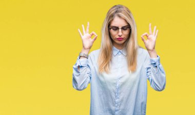 Genç güzel sarışın iş kadın gözlük izole arka plan üzerinde dinlenmek ve gülümseyen gözlerle kapalı parmak jestle meditasyon yapıyor. Yoga kavramı.