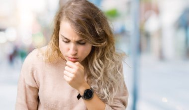 Sweatershirt duygu hasta ve soğuk veya bronşit için semptom olarak öksürük izole arka plan üzerinde giyen güzel genç sarışın kadın. Sağlık kavramı.