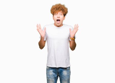 Çılgın ve silah ile başarı için hayran kutluyor casual beyaz t-shirt giyen afro saçlı yakışıklı delikanlı kaldırdı ve açık gözleri çığlık heyecanlı. Kazanan kavramı