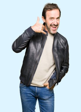 Siyah deri ceket gülümseyen giyen orta yaş yakışıklı adam el ve parmak telefonda konuşmak ile telefon jest yapıyor. Kavramları iletişim.