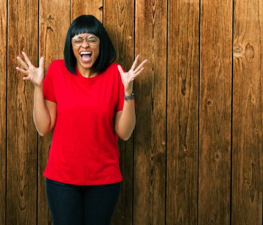 Arka plan deli kutluyor güzel genç Afro-Amerikan kadın üzerinde gözlük takan izole ve crazy arms ile başarı için kaldırdı ve heyecanlı çığlık gözler kapalı. Kazanan kavramı