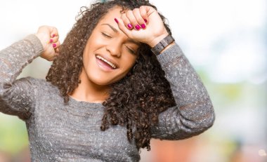 Kıvırcık saçlı genç güzel kadın gri kazak giyen dans mutlu ve neşeli, hareketli rahat ve kendinden emin müzik dinleme