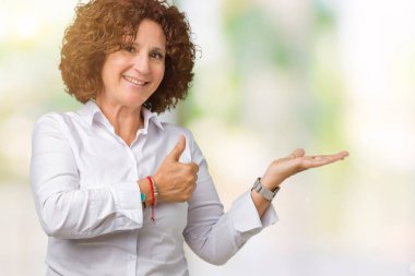 İzole arka plan gösteren palm el ve yukarıya, mutlu ve neşeli gülümseyen baş parmakları Tamam jest yapıyor güzel orta ager üst düzey businees kadın