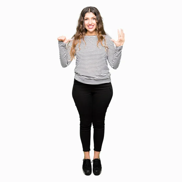自信を持って幸せそうに微笑みながら 6番の指で見せ 指を上げるストライプのセーターを着た若い美しい女性 — ストック写真