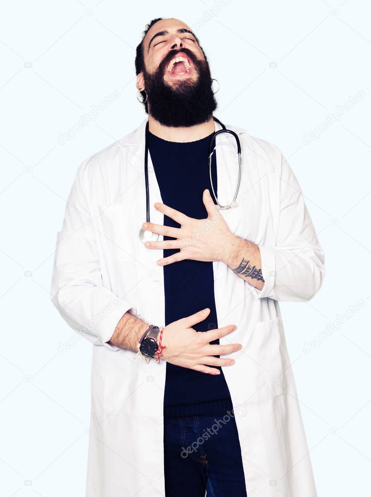 Doctor with long hair wearing medical coat and stethoscope Smiling and laughing hard out loud because funny crazy joke. Happy expression.
