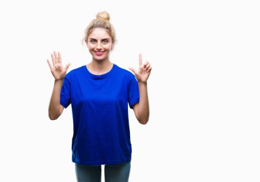 Gösterilen ve parmakları ile işaret izole arka plan üzerinde mavi t-shirt giyen genç güzel sarışın ve mavi gözlü kadın kendinden emin ve mutlu gülümseyerek süre yedi numara.