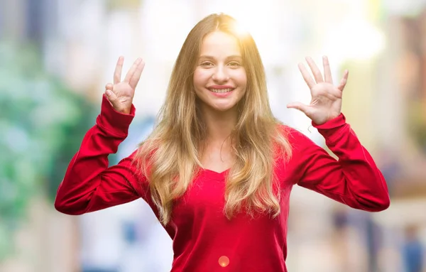 孤立した背景表示と指で上向きに赤いセーターを着ている若い美しいブロンドの女性数 自信を持って 幸せな笑みを浮かべて — ストック写真