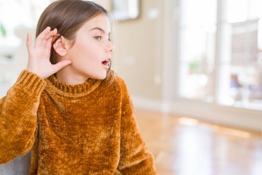 Güzel genç kız çocuk rahat kazak giyen el kulak üzerinde bir işitme dinleme ile gülümseyerek söylenti veya dedikodu. Sağırlık kavramı.