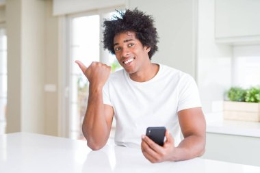 Afrikalı Amerikan adam akıllı telefon işaret ve mutlu yüz gülümseyen yan başparmak ile gösteren kullanarak