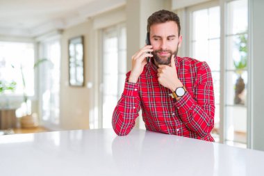 Yakışıklı adam akıllı telefon ciddi yüz soru hakkında düşünme konuşurken, çok karışık bir fikir