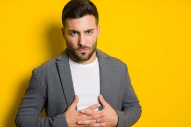 Genç yakışıklı adam possing ve modelleme sarı izole bac üzerinde