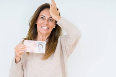 Tecrit edilmiş arka plan üzerinde 50 liralık banknot tutan orta yaşlı kadın, eliyle başını gerdi, utanç ve sürpriz yüzle şoke oldu, kızgın ve hüsrana uğradı. Korku ve hata için üzgün.