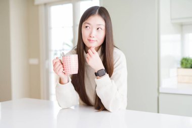 Güzel Asyalı kadın kahve ciddi yüz soru hakkında düşünme bir fincan içme, çok karışık bir fikir