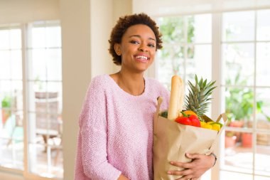 Kağıt torba dolu tutan genç güzel Afrikalı-Amerikalı kadın