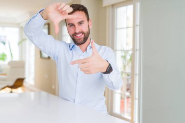 Elle yapma çerçeve ve parmakları ile mutlu yüz gülümseyen yakışıklı iş adamı. Yaratıcılık ve Fotoğrafçılık kavramı.