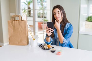 Akıllı telefon kullanarak uygulamadan gıda teslimatı sipariş güzel genç kadın soru hakkında ciddi yüz düşünme, çok karışık bir fikir