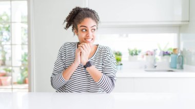 Afro saçlı güzel afro-amerikan kadın rahat çizgili kazak sinirli gülüyor ve yan bakan çene elleri ile heyecanlı