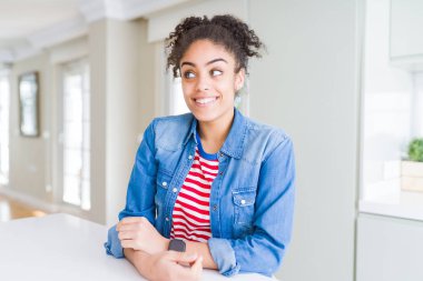 Afro saçlı rahat denim ceket görünümlü yan ve dik dik bakma uzağa düşünce gülümseyen güzel genç Afro-Amerikan kadın.