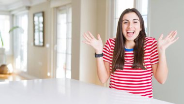 Rahat çizgili t-shirt giyen güzel genç kadın deli kutluyor ve kollarını kaldırdı ve açık gözleri heyecan çığlık ile başarı için hayran. Kazanan kavramı