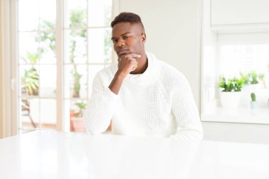 Afro-Amerikan yakışıklı beyaz masada emin çapraz kollar ve çeneme kaldırdı el ile gülümseme ile kameraya bakıyor. Pozitif düşünce.