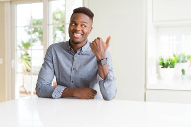 Beyaz masa arıyorum ve başparmak yanında yukarıyı mutlu yüz ile gülümseyen yakışıklı Afrikalı-Amerikalı adam.