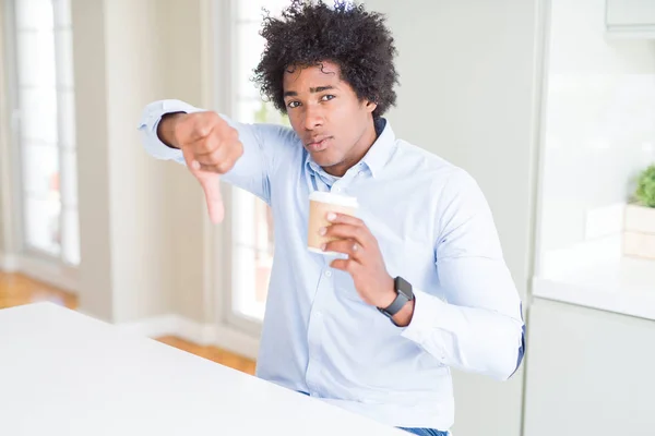 African American man with afro hair drinking a take away cup of coffee with angry face, negative sign showing dislike with thumbs down, rejection concept