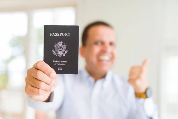 中年男子拿着美国护照指着 用大拇指向一边露出开心的脸微笑 — 图库照片