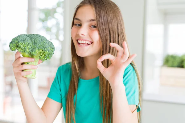 新鮮なブロッコリーを食べる美しい若い女の子は 指でOkサインをやって 優れたシンボル — ストック写真