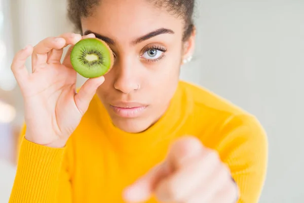 若いアフリカ系アメリカ人の女の子食べる緑のキウイ指差しで指でカメラとあなたに 手のサイン 正と自信を持ってジェスチャーからフロント — ストック写真