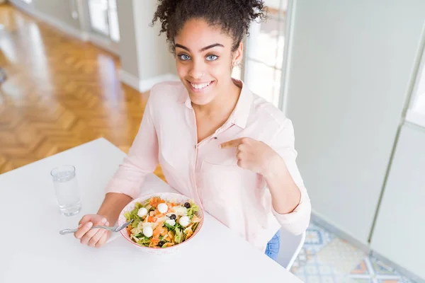 若いアフリカ系アメリカ人女性が健康的なパスタサラダを食べて 驚きの顔で自分自身を指差す — ストック写真