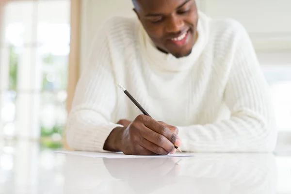 Primer plano del hombre africano escribiendo una nota en un papel sonriente confid — Foto de Stock