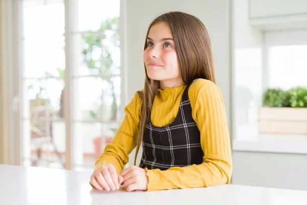 若いです美しいですブロンド子供女の子身に着けていますカジュアルな黄色セーターホーム笑顔見ますへザ側と見詰める離れて考え — ストック写真