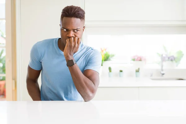 英俊的非洲裔美国男子穿着休闲T恤在家里看起来紧张和紧张与手咬指甲 焦虑问题 — 图库照片