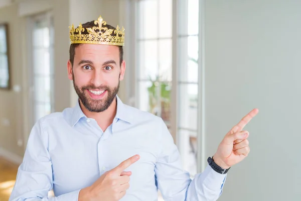 英俊的商人戴着金色的皇冠作为国王或王子微笑 看着相机指着两只手和手指的一面 — 图库照片