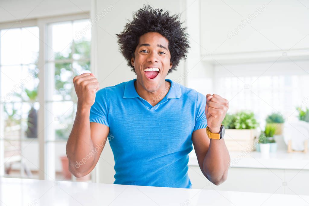 African American man at home very happy and excited doing winner gesture with arms raised, smiling and screaming for success. Celebration concept.