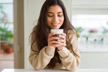 Güzel genç kız evde bir fincan kahve içme ve gülümseyen