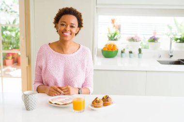 Genç Afro-Amerikan kadın sabah kahvaltısını evde mutlu ve serin bir gülümsemeyle yiyor. Şanslı kişi..