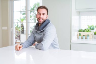 Evde rahat sweatshirt giyen ve olumlu gülümseyen yakışıklı adam