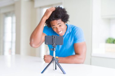 Baş, el ile vurguladı smartphone kullanarak web kamerası ile online arama yapan Afro-Amerikan erkek şok utanç ve sürpriz suratla, öfkeli ve sinirli. Korku ve hata için üzgün.