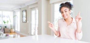 Afro saçlı, kendine güvenen ve parmaklarını farklı yönlere çeviren güzel Afro-Amerikan kadını geniş açılı. Reklam için boşluk kopyala