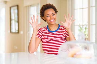 Genç güzel Afrikalı-Amerikalı kadın evde gösterilen ve parmak sayısı on kendinden emin ve mutlu gülümseyerek süre ile yukarı dönük.