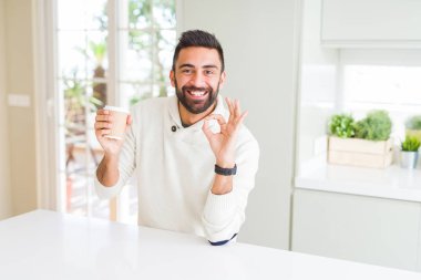 Yakışıklı İspanyol adam parmakları ile ok işareti yapıyor bir kağıt fincan bir kahve içme, mükemmel sembolü