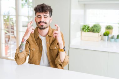 Sıradan bir ceket giyen genç adam beyaz masada oturuyor umut ve gözleri kapalı parmaklarını çaprazlayarak gülümsüyor. Şans ve batıl inanç..
