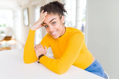 Güzel genç Afrikalı Amerikalı kadın neşeli masada rahat eğilerek gülümseyen