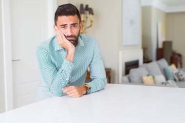Yakışıklı İspanyol adam evde yorgun görünümlü ve çapraz kolları ile depresyon sorunları ile sıkılmış düşünme.